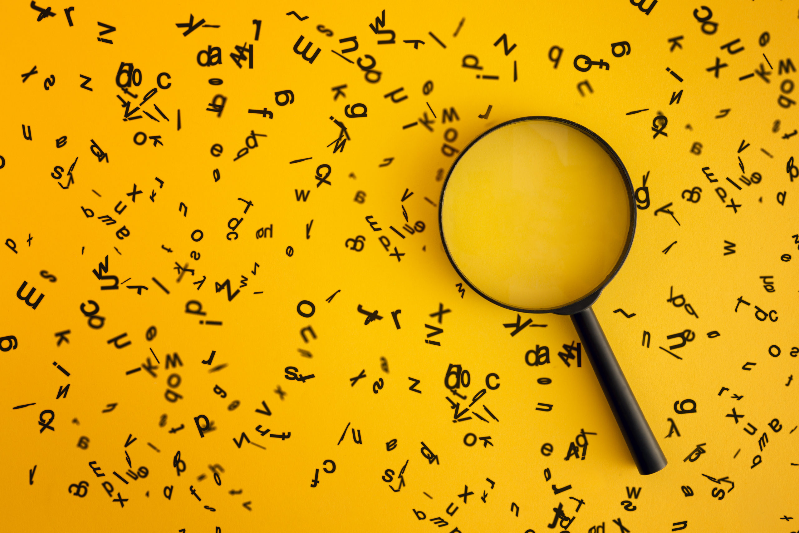 Magnifying With Wooden Alphabets Around On Yellow Background